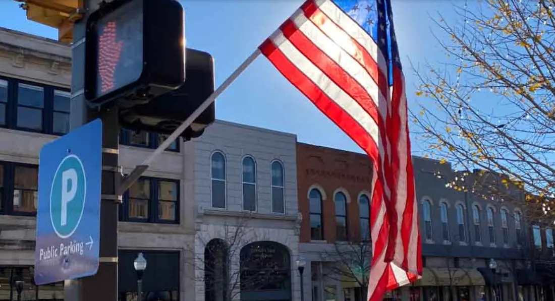 American flag hanging over brick storefronts on a downtown street in Lawrence, Kansas