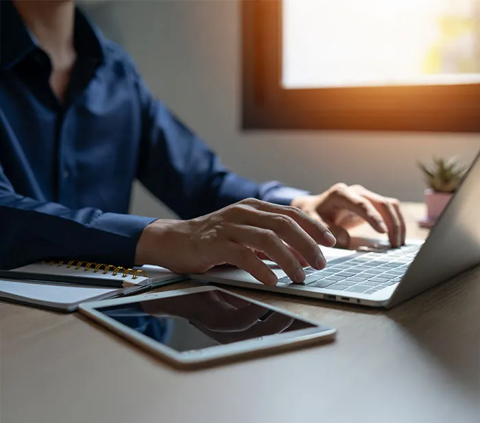 Person opening an OWNx account on a laptop at a desk beside a tablet