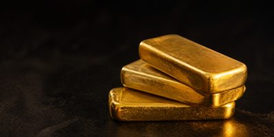 A stack of gold bullion bars on a dark surface, representing physical gold you actually own
